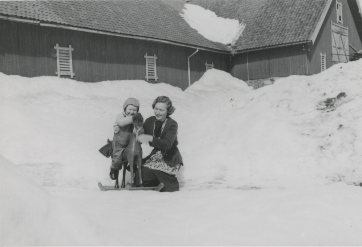 Randi Braate med Leif Martin Braate og gyngehest ute i snøen på Bråte Gård i Gjerdrum.