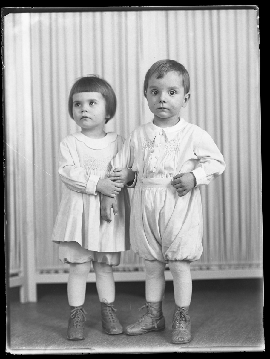 En flicka står och håller i sin brors arm. I fotografens anteckningar står det "Ing.[enjör] Bergs barn", tolkat som tvillingarna Peter Wilhelm och Ulla Maria.