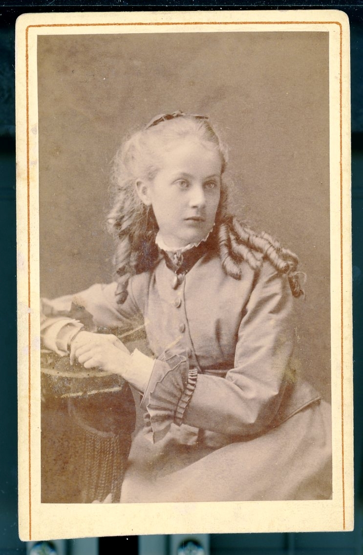 Kabinettsfotografi: fröken Sigrid Gyllencreutz, en ung flicka lockar i håret sittande i en fåtölj.
