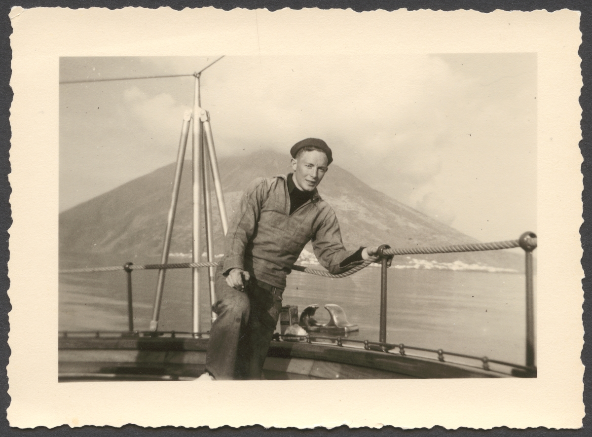 Porträtt av Evert Ingemansson i arbetsuniform som står vid reling av yacht Sea Cloud. I bakgrunden syns vulkanen Stromboli.