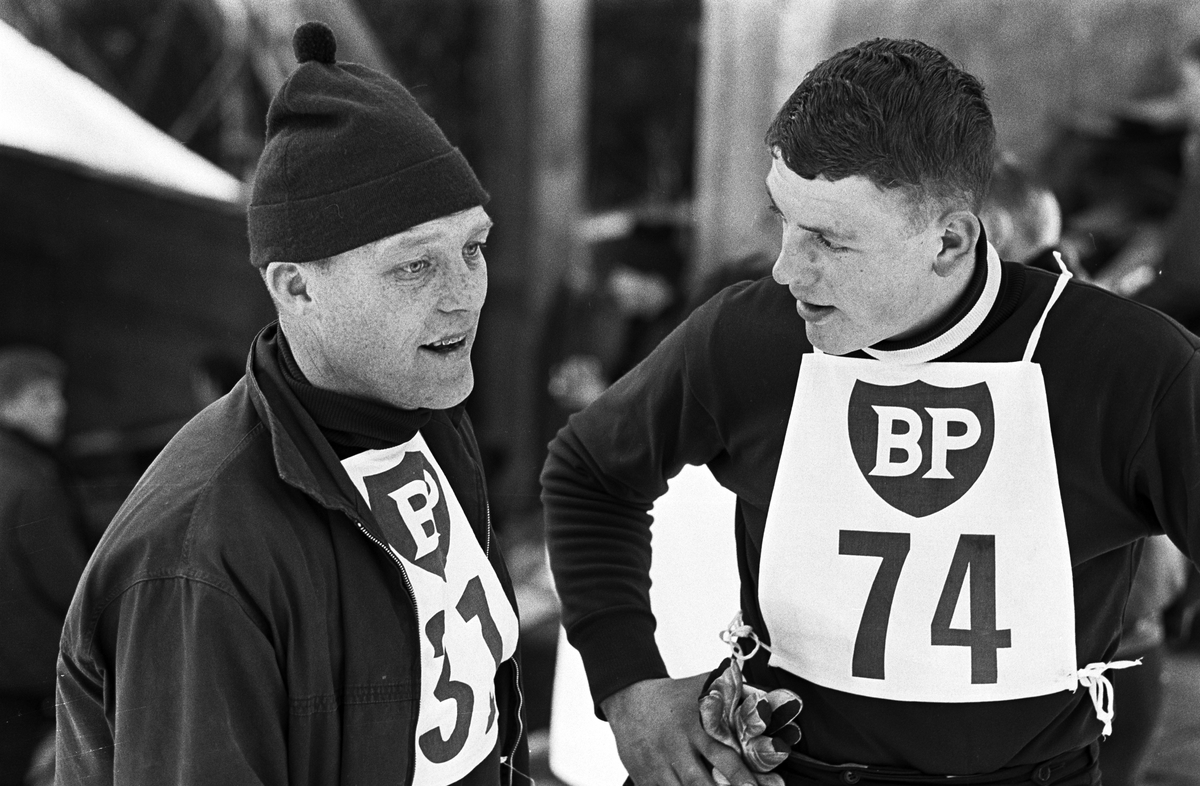 Lars Grini og en annen skihopper prater, NM ski i liten bakke 1965, Midtstubakken. Fotografert 21. februar 1965.