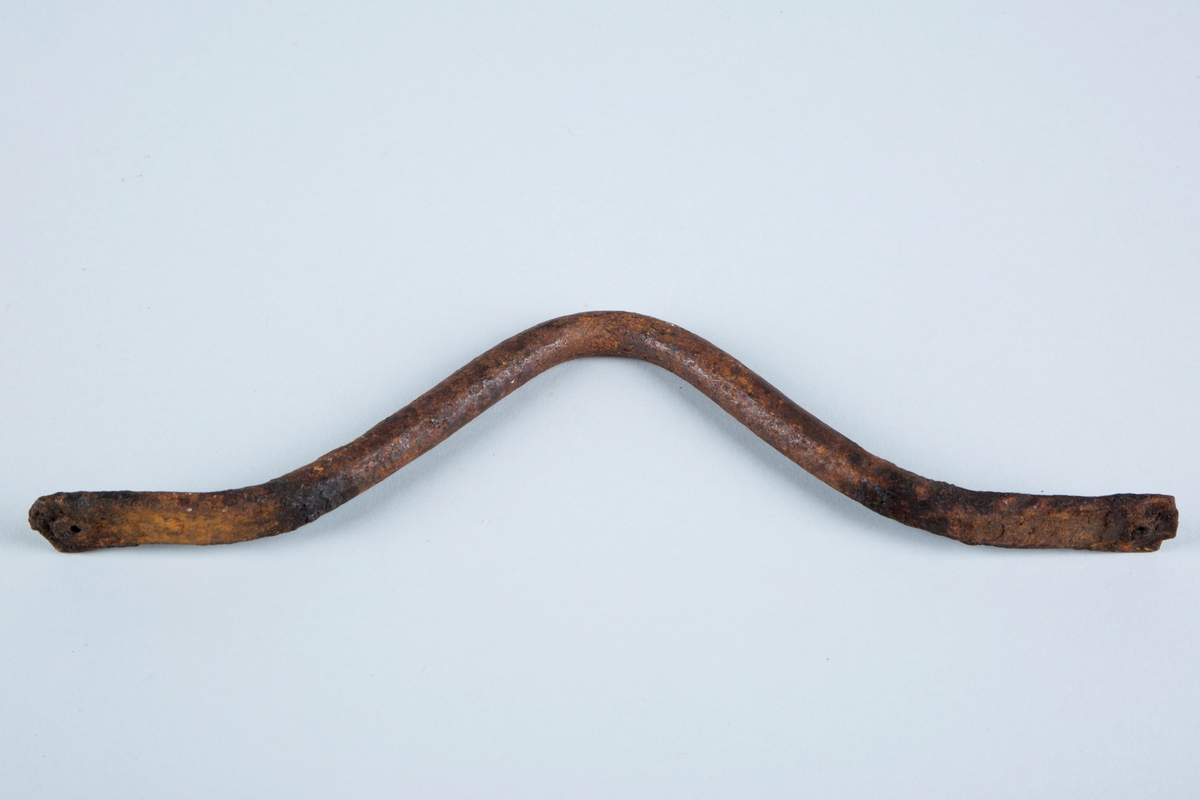 Håndtak laget av jern.
Formet som en bue, har hull for feste av f.eks skruer i begge ender