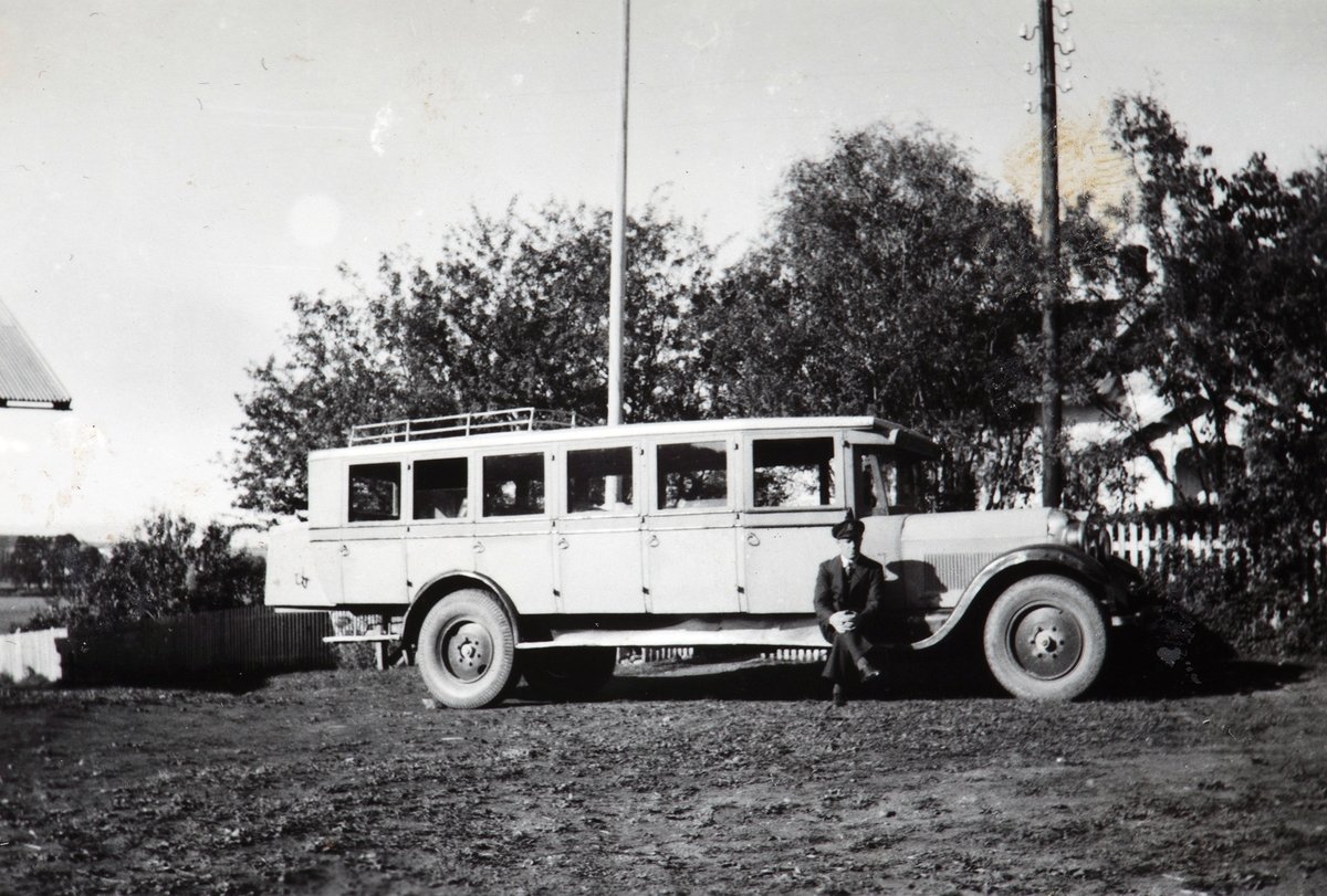 Første bussen som Conrad Pedersen hadde. Han sitter på stigbrettet. Ca 1930