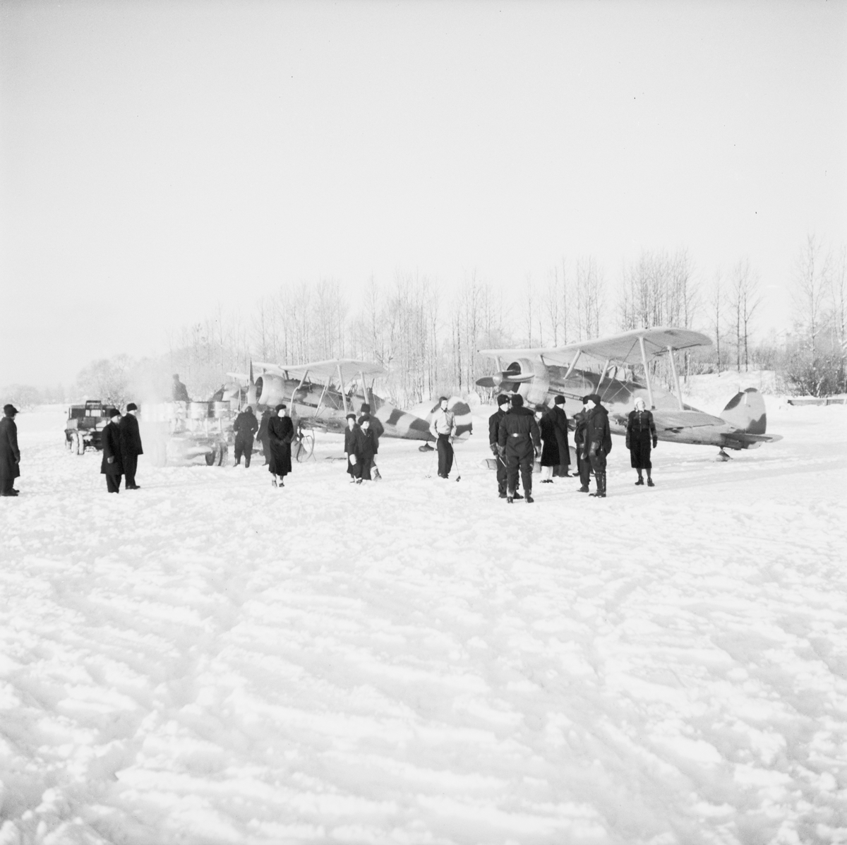 Militärer och Ljusdalsbor samlade på flygfältet på Kyrksjöns is i Ljusdal den 1 januari 1940. I bakgrunden står två flygplan Gloster Gladiator. Flygplanen flög senare vidare till Svenska frivilligkåren i Finland, F 19.