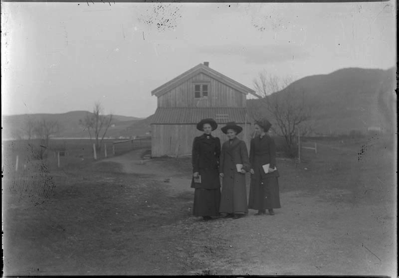 Tre unge kvinner i kåper og hatter, utenfor huset på Dolstadsjøen.