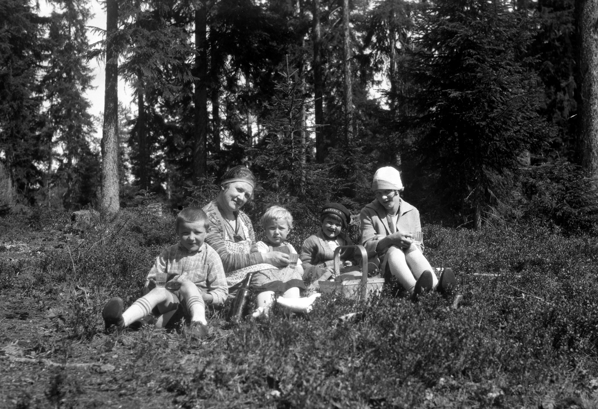 Kvinne med fire barn sitter i skogen.