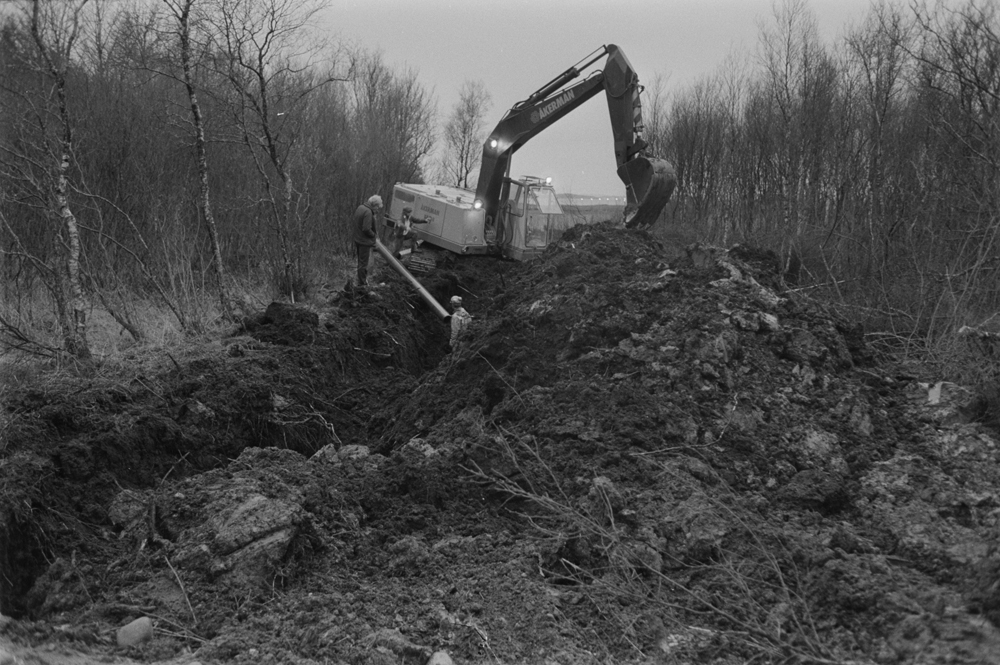 Legging av vannledning til Søvik. Åkerman H9 gravemaskin som graver grøft og personer.