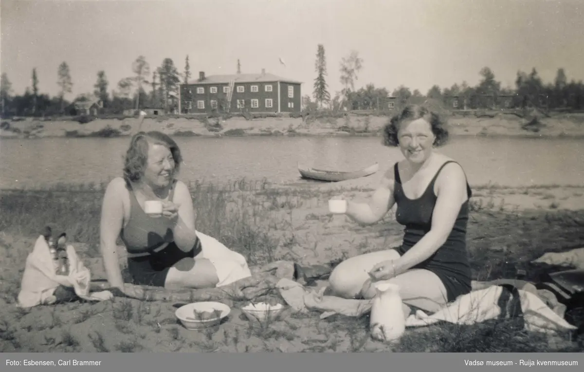 Gunvor Moe og Dagny Engelsen på stranda på ferie i 1935. I bakgrunn hotellet i Ivalo. 