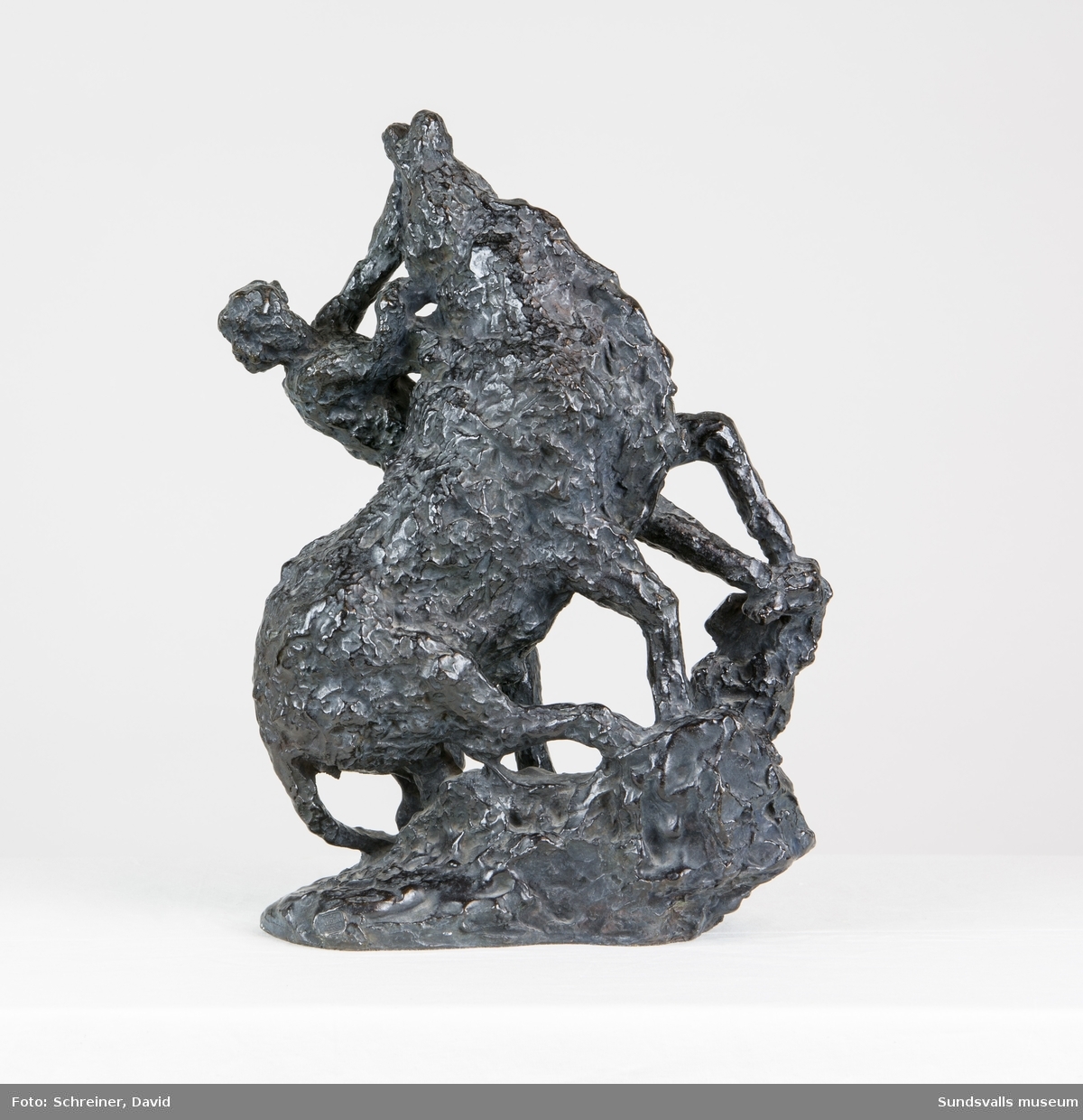 En skulptur i form av en man i kamp med en tjur där mannen i en kraftfull rörelse tvingar tjurens huvud uppåt och bakåt.