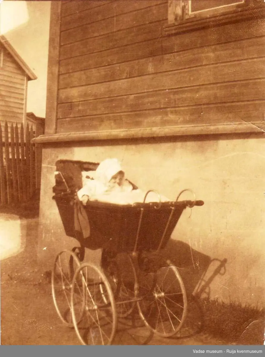 Edna Christensen i barnevogn foran Piippohuset i Havnegt. 27 i Vadsø 1920. 