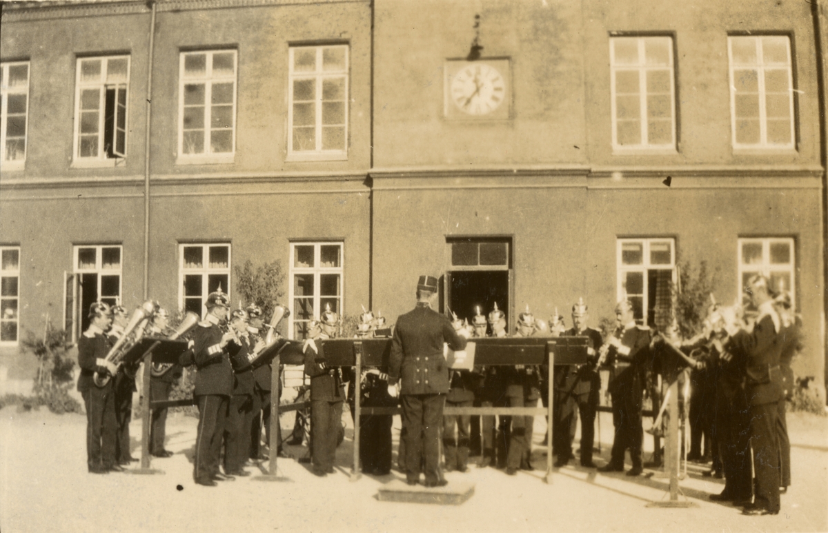 Göta livgardes musikkår ger konsert på kaserngården på Linnégatan, matsal och skolbyggnaden i bakgrunden.