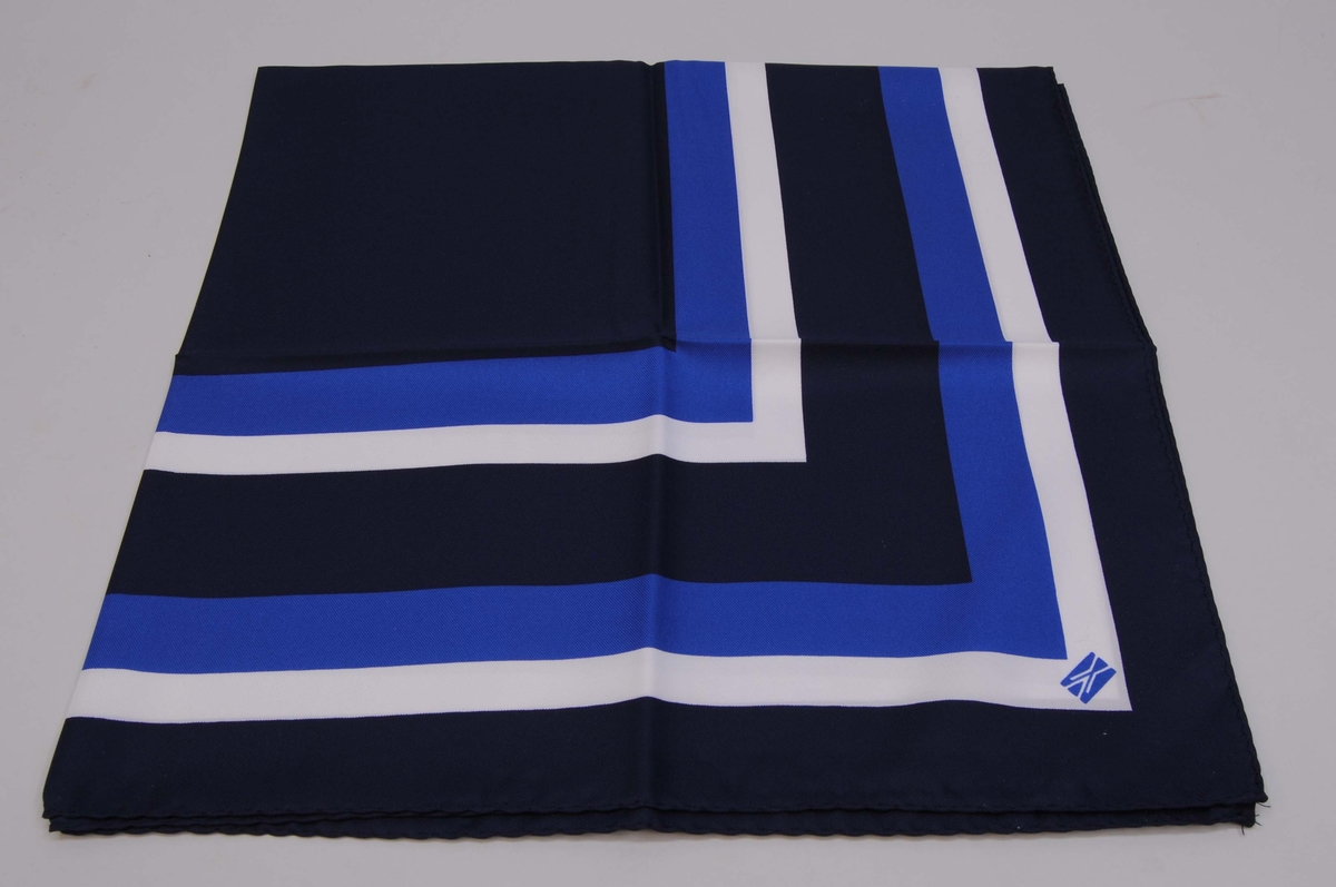 Scarf (:1) av polyester i mörkblått, blått och vitt med Banverkets logotyp. Förvaringsetui av vit kartong (:2).