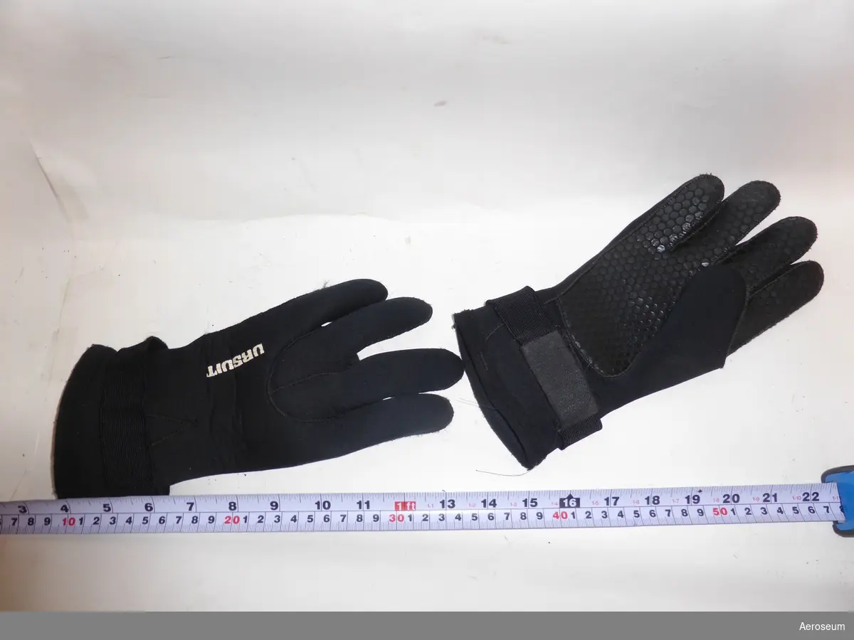Handskar tillhörande Ytbärgardräkt (den registrerad som AERO.002159:1). De är svarta med blått foder. På handskarna står det i vitt: "URSUIT"