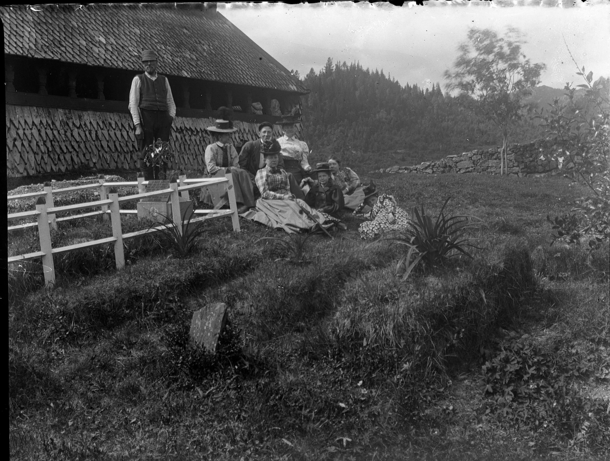 Gruppeportrett utenfor Eidsborg Stavkirke. Anders Johnsens familie med graver i forgrunnen. Mannen til venstre ved kirken er Olav Vindlaus. Han var kirketjener, omviser og nærmeste nabo til kirken.

Antatt fotosamling etter Anders Johnsen.