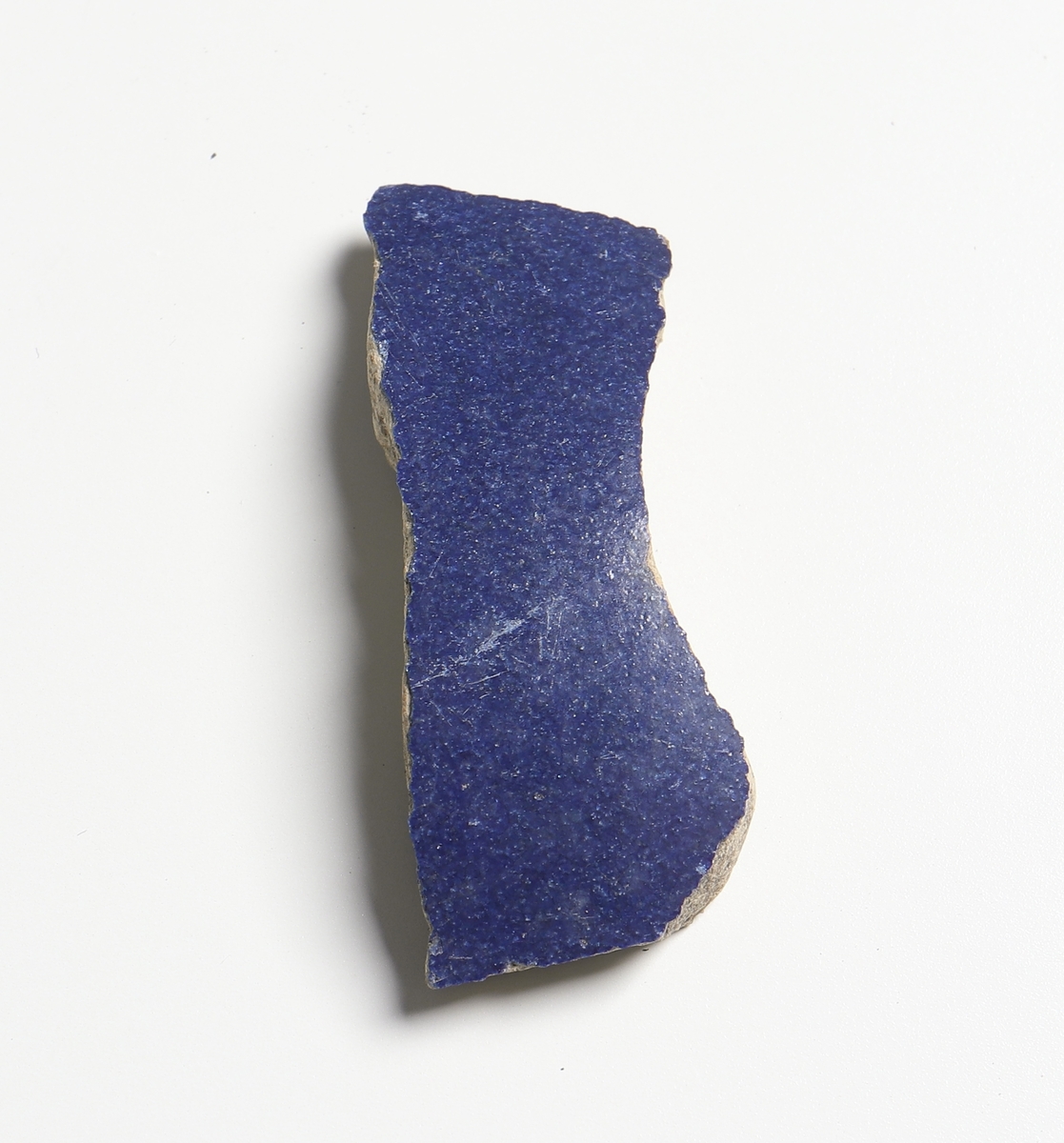 Bukbit av fajanskärl med blå ytterglasyr. Gråbeige glasyr på skärvans insida. Sammanhör troligen med 2497, 2503 - 2515, 2525-2531 och 2535. Antagligen en så kallad Mallingkanna. Tillverkad i Holland år 1575 - 1625.