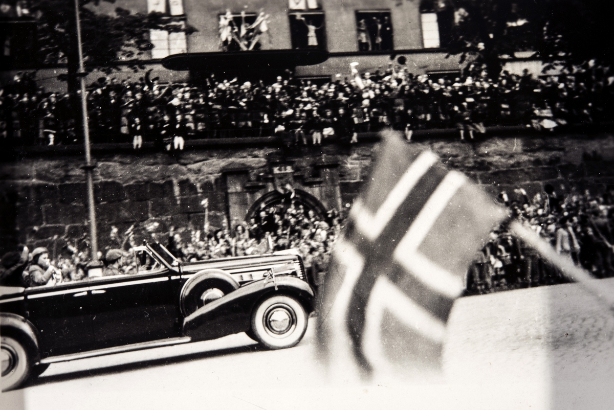 Kronprinsen vinker fra bilen i paraden på vei opp Karl Johans gate i Oslo våren 1945.