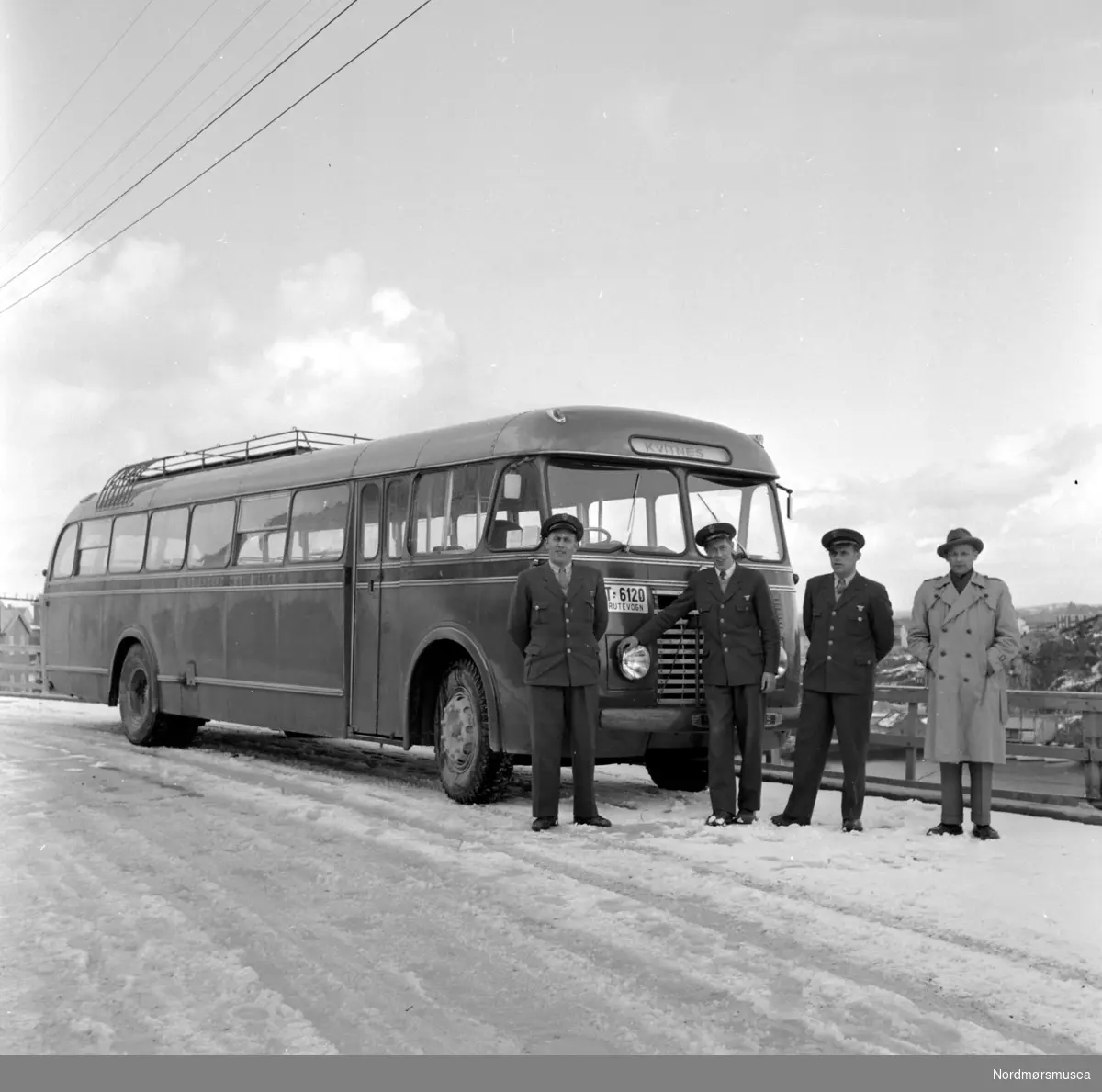 Rutebuss med skilt T-6120 fra Kristiansund og Frei billag med sjåfører stående like ved. Bussens destinasjon er satt til Kvitnes. Datering er trolig mellom 1950-1960. Fotograf er Nils Williams i Kristiansund. Fra Nordmøre museums fotosamlinger.