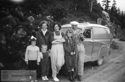 Familie foran bil langs fjellvei
