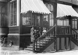 Blidensol. Familien Johnsen på trappen foran glassveranda