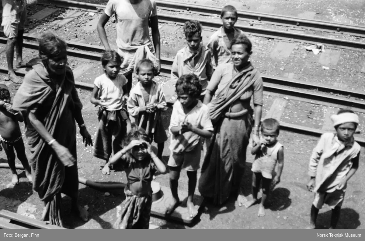 En gruppe mennesker, barn og voksne, ved jernbanespor