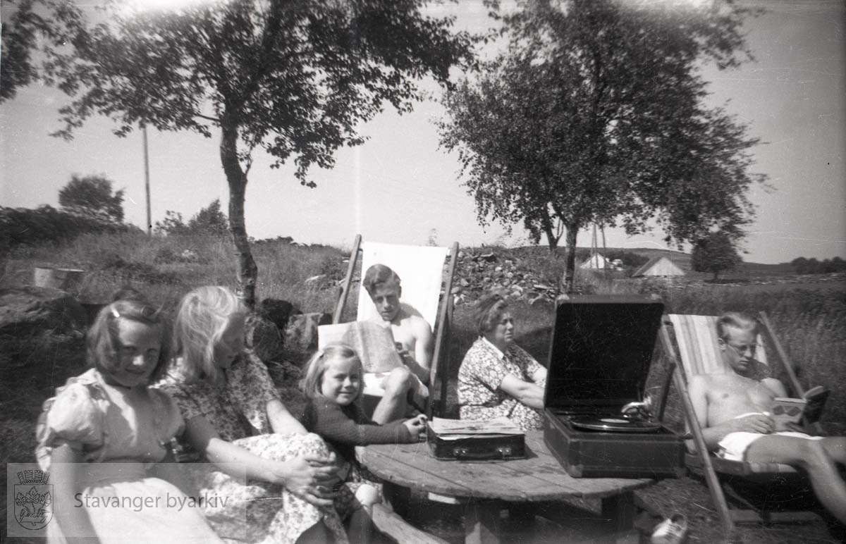 I fluktstol t.v: Per, Ellinor Iversen (mor til Per og Jan) og Jan t.h..De leide sommerhus/ hytte på Bru. .En grammofonspiller står framme på bordet.