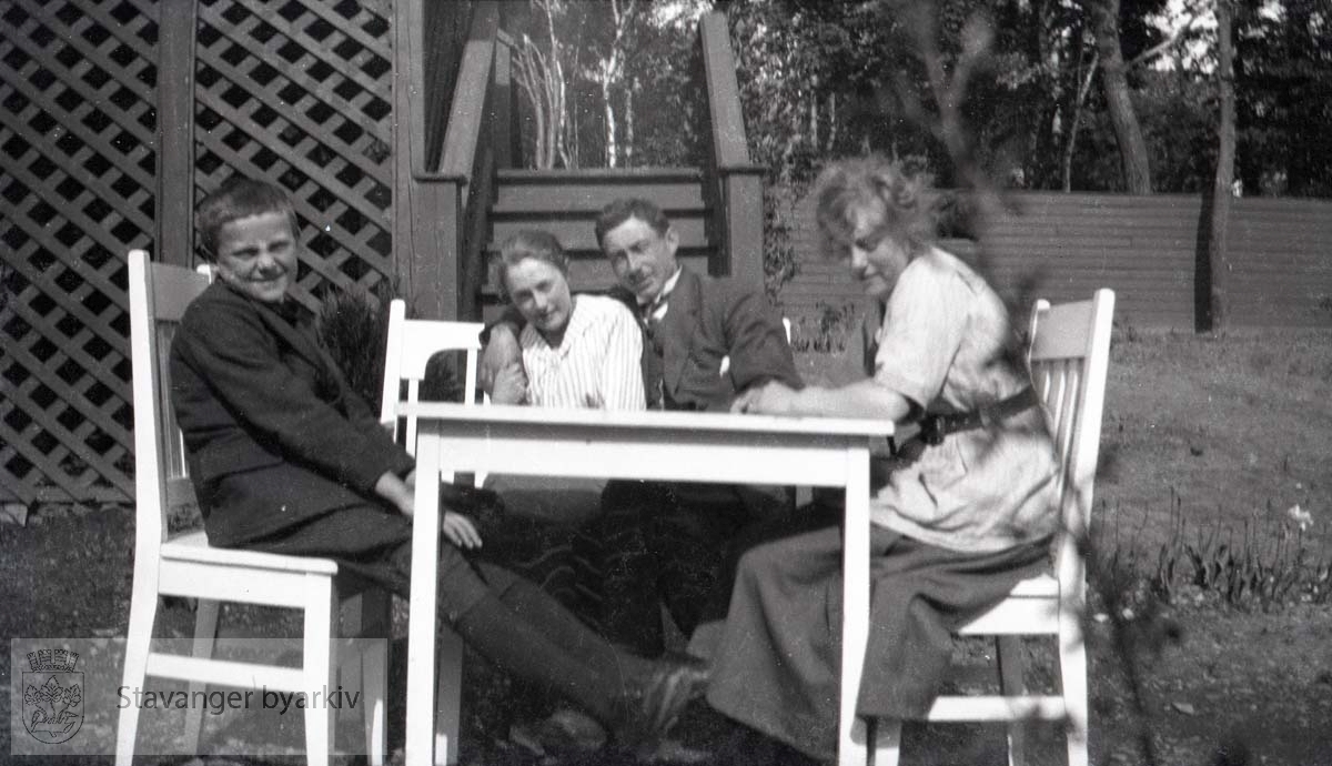 Fire personer samlet rundt bord i hagen