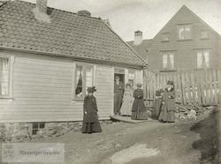 Fem kvinner og en mann ved inngang til hus