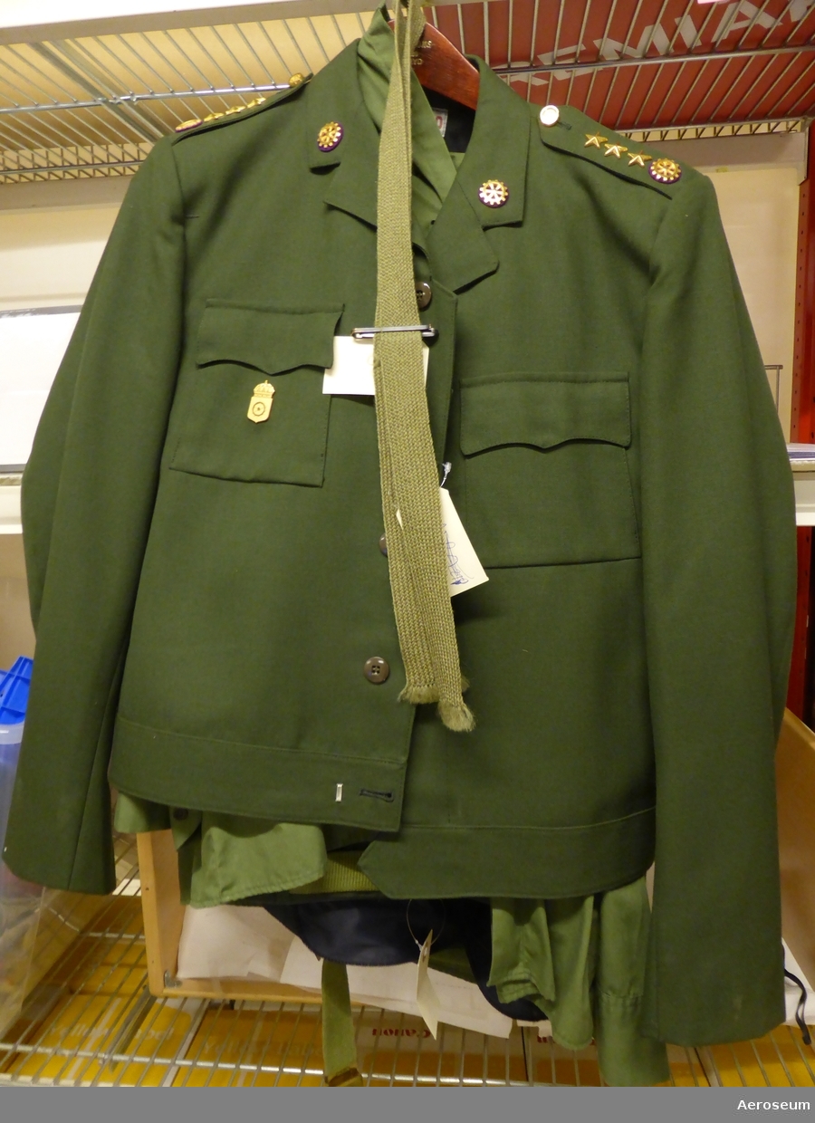 En komplett kaptensuniform från svenska armén. Troligtvis från tekniska kåren. Består av en grön tygslips med slipshållare i metall, ett par gröna byxor och grönt skärp, en grön skjorta, en grön jacka, och en grön kaptensmössa. Skjortan är storlek 39, jackan är storlek C 50, och byxorna är storlek C 52.

Det finns en datummärkning i kaptensmössan: "1969", och en i jackan: "1971". I en innerficka i jackan sitter det 2 bläckpennor och en stiftpenna. På skjortans och jackans axlar sitter det tre stjärnor och ett antal kugghjulsymboler. På jackan sitter även ett tjänstgöringstecken från "Arméns tekniska centrum". På kaptensmössan sitter ett metallmärke som visar att det var armén (två svärd som korsar varandra). Innuti kaptensmössan finns namnet "Christer Lagert" och två olika adresser.