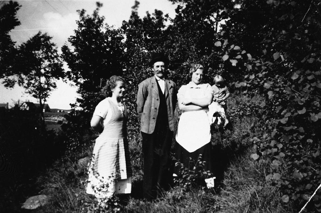 F.v. Ellen Lode, Nils Tønnesson Kalberg (sør) og Maria Lode i hagen mellom husa til Georg Lode og Gustav Lode