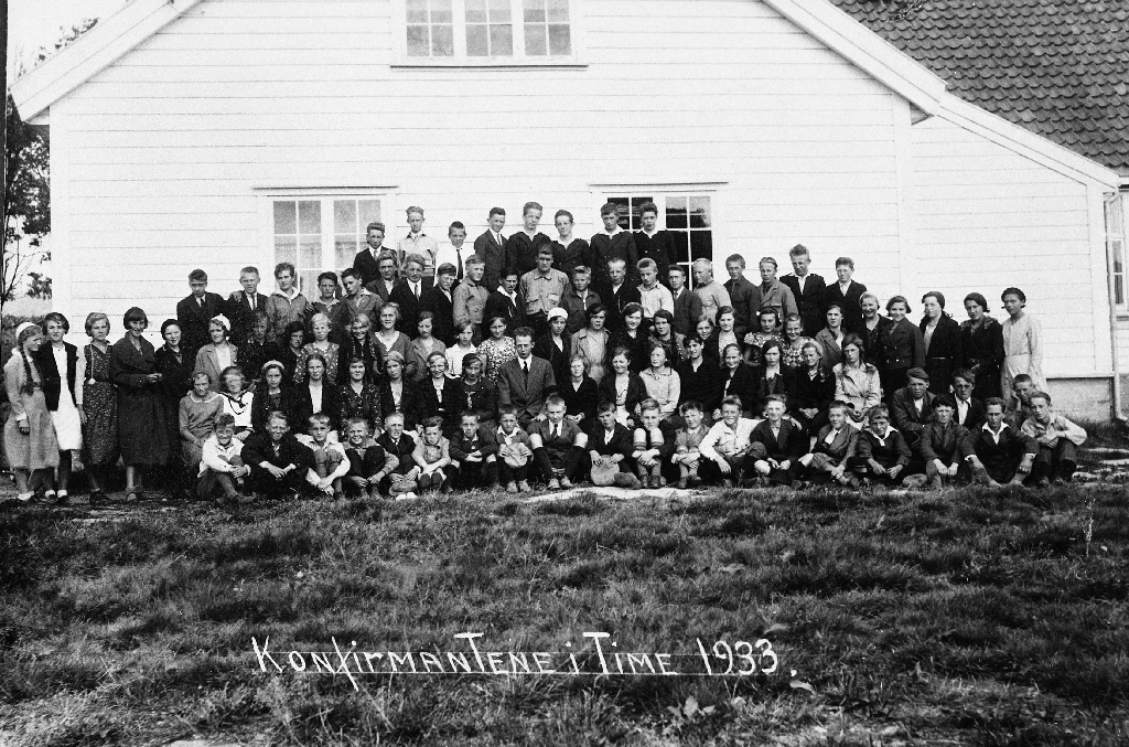 Konfirmantane i Time 1933 utanfor ungdomshuset på Time. Sokneprest er Kåre Hognestad.