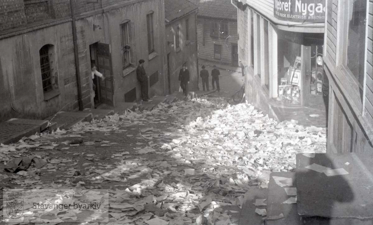Tatt kort tid etter frigjøringen fra okkupasjonen , .2. verdenskrig..Fredsdagene 1945.. .Papirer flyter i gatene etter at kontorene til Nasjonal Samling ( NS ) i Kirkegata 2 har blitt raidet...