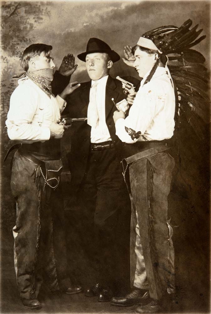 Postkort med tre menn; én kledd som cowboy, én som banditt, og én indianer. Påskrift bak: "Ole M. Nyland (?), Johan eller Egil Avdem, Isak Utnes. Tatt i Amerika."
