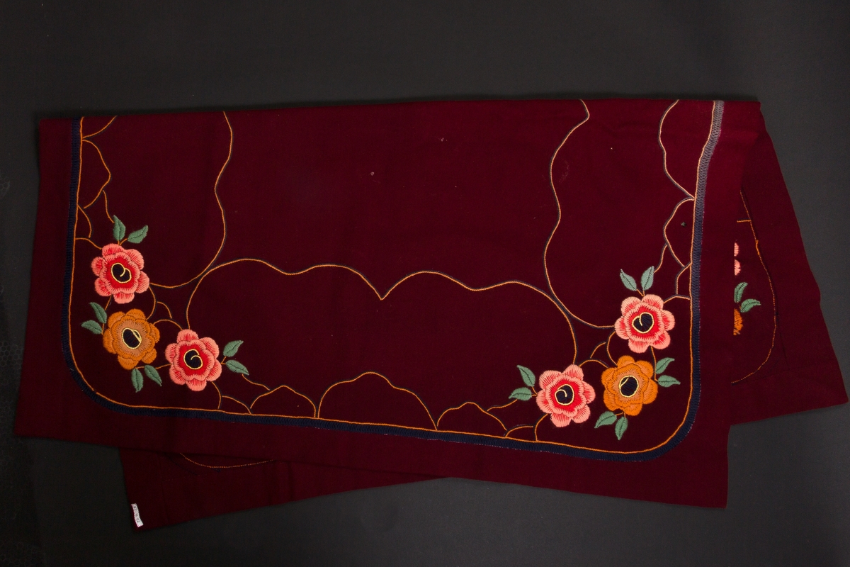 Firkantig, burgunder bordduk. Dekorert med broderte blomster og ramme.