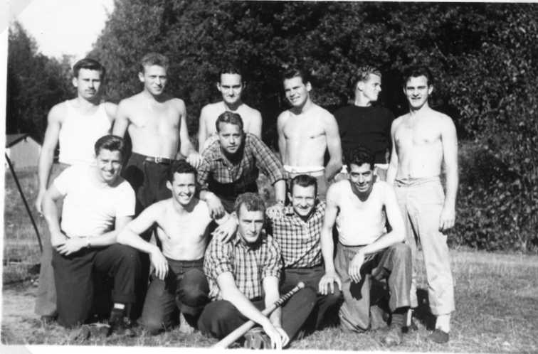 Tolv män på "lagbild", flertalet med bar överkropp. I mitten sitter en med ett slagträ för baseball. Troligen på Åsavallen, Grännaberget.