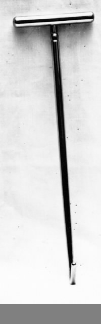 Förlossningsinstrument av förkromat stål, så kallad trubbig hake. Rund stång av förkromat stål, i ena änden uppvikt till att forma en hake, den andra änden försedd med T-handtag.