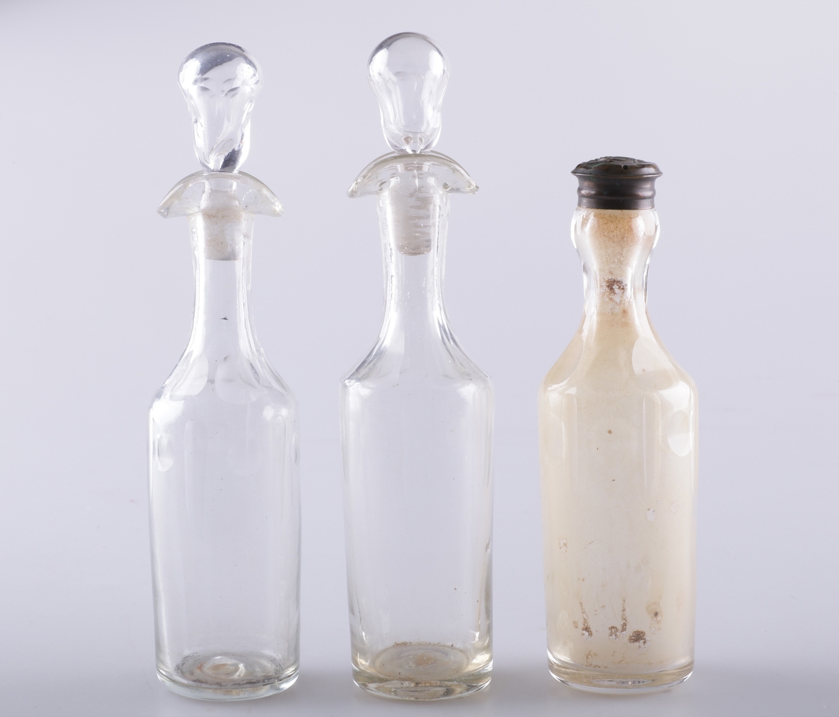 Flasken er slank med dobbel helletut og glasspropp. Den er dekorert med fassettsliping og olivensliping i annethvert felt øverst på kroppen.