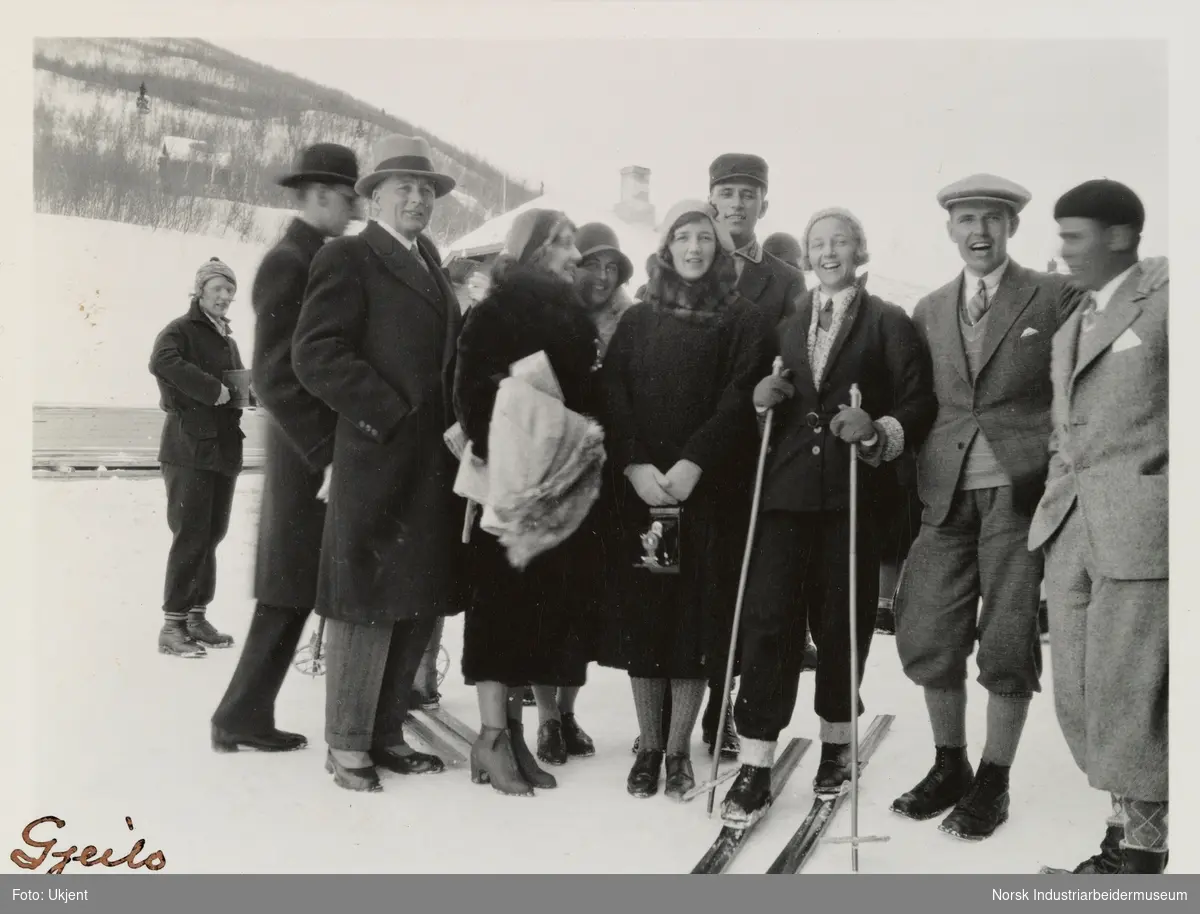 Gruppe med mennesker utendørs på Geilo i 1931. To mennesker står på ski, en annen kvinne holder et fotografiapparat i handen.
