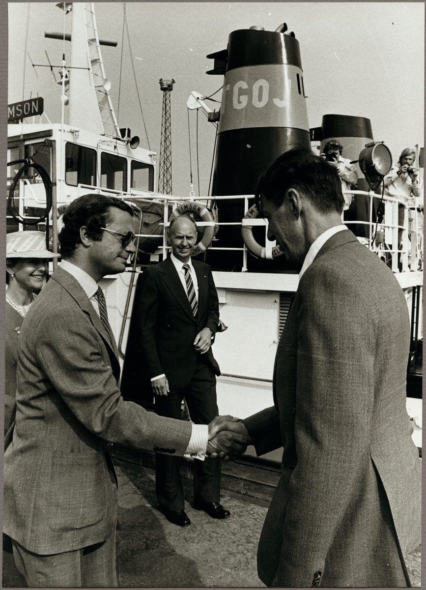 Magnus Värmon skakar hand med Kung Carl den XVl Gustaf och Drottning Silvia. De står bredvid Trafikaktiebolaget Grängesberg - Oxelösunds Järnvägar, TGOJ:s bogserbåt "Simson", som ligger förtöjd vid kajen i Oxelösunds hamn den 9 september 1980.