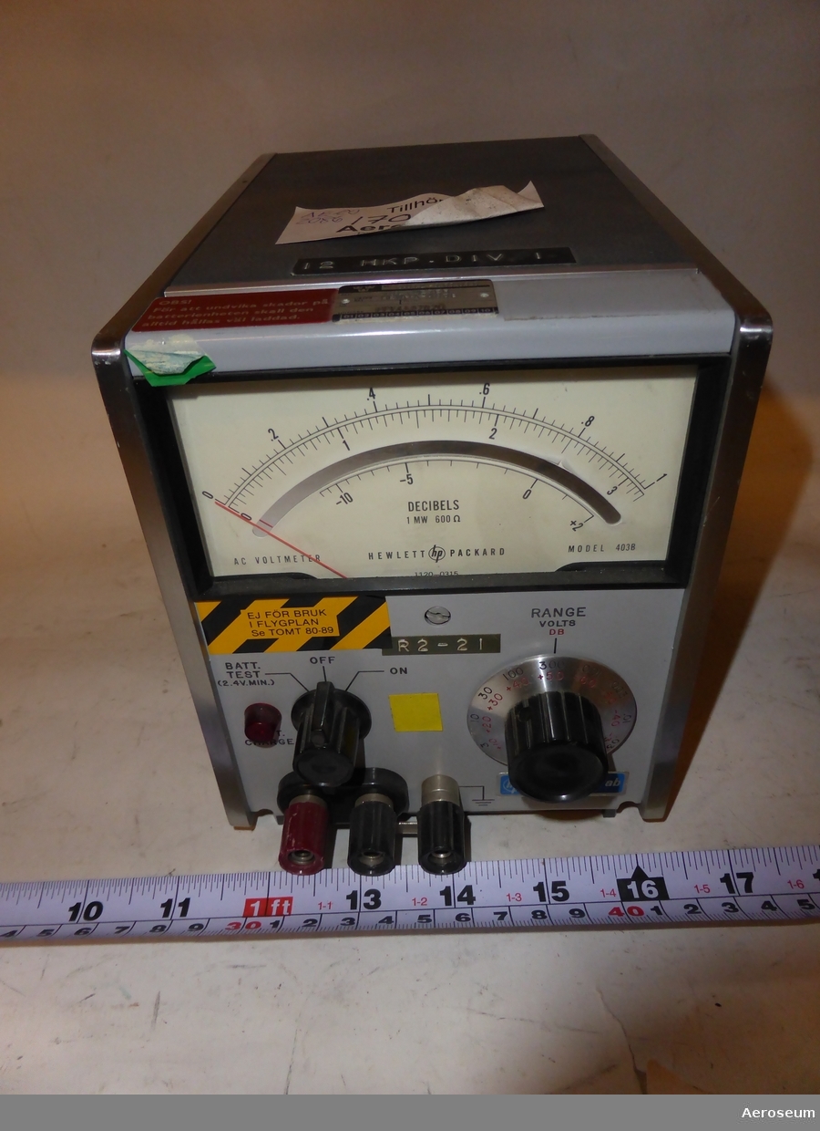 En voltmeter i grå metall. Tillverkad av Hewlett-Packard Instrument AB. På föremålet är "12 HKP. DIV TELE" inristat, det finns också en tejp där det står: "12 HKP. DIV I".