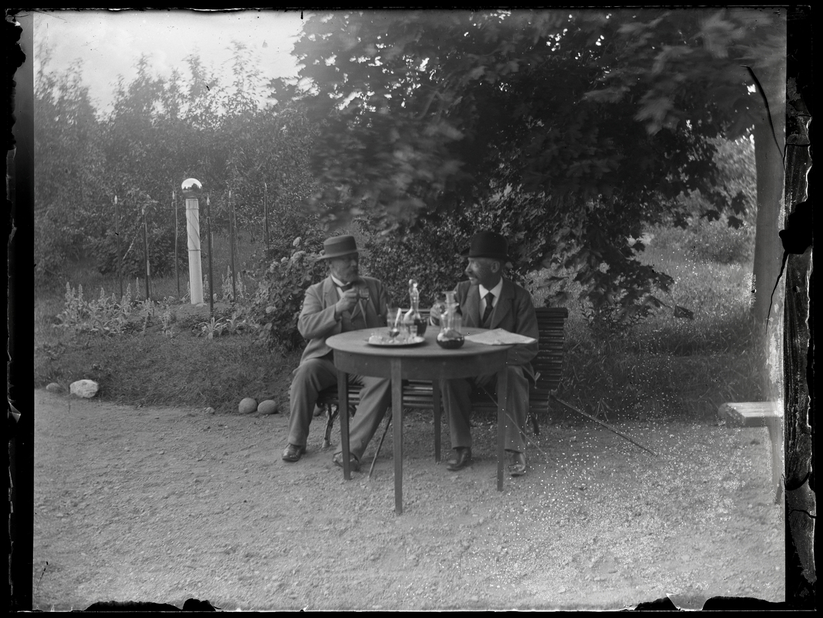 Två män vid trädgårdsbord, Riddarhyttan.