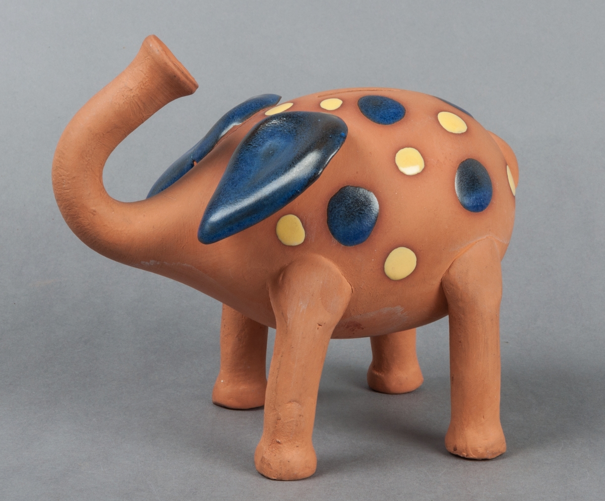 Sparbössa i form av elefant, halvglaserad med mönster i blått och gult, lergods.