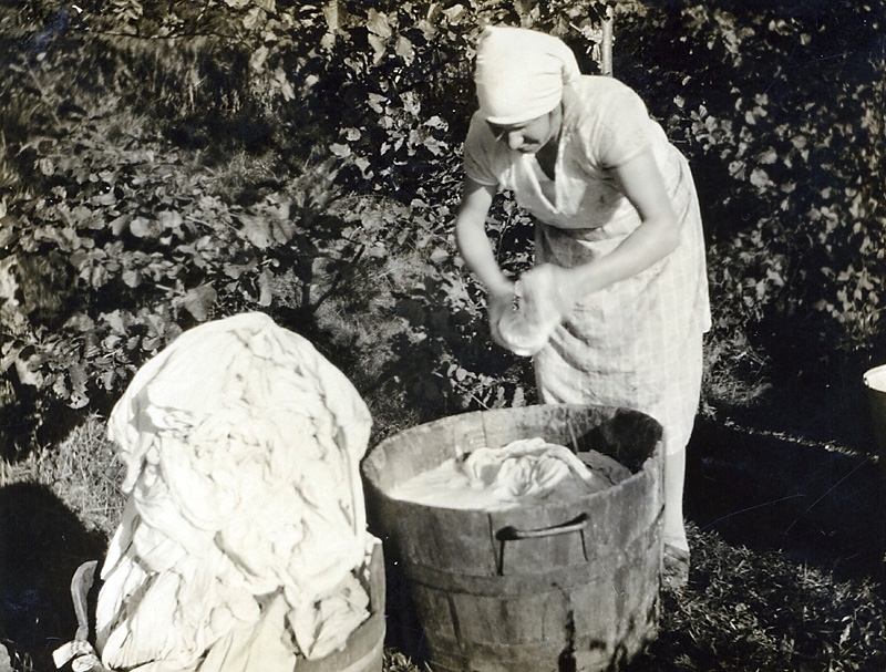Gurli Bengtsson (1902 - 1993) tvättar kläder och lakan i en tvättbalja, Vommedal Västergård 3:3 "Hanses" 1928. Gurli arbetade som hushållerska hos bröderna Gustav och Albert Bengtsson.
