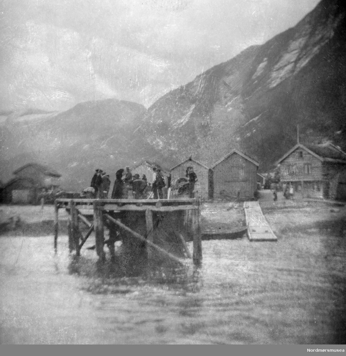 Foto fra en brygge, trolig et sted i Romsdal. Fra Sverdrupsamlingen ved Nordmøre museums fotosamlinger.