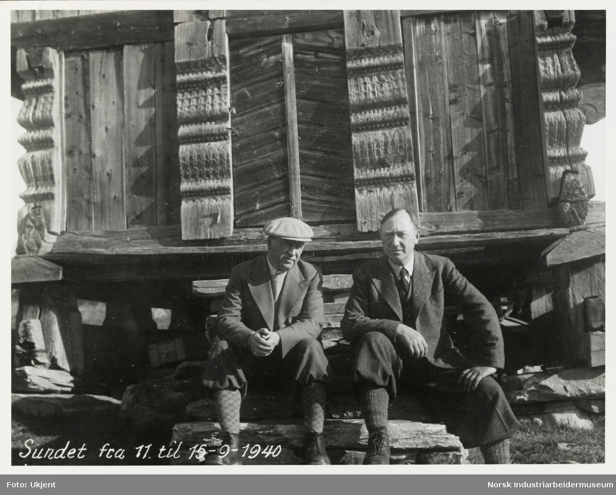 James Coward og en mann iført turantrekk sitter på trappen til Ellefstjønnburet på Sundet, Møsstrond