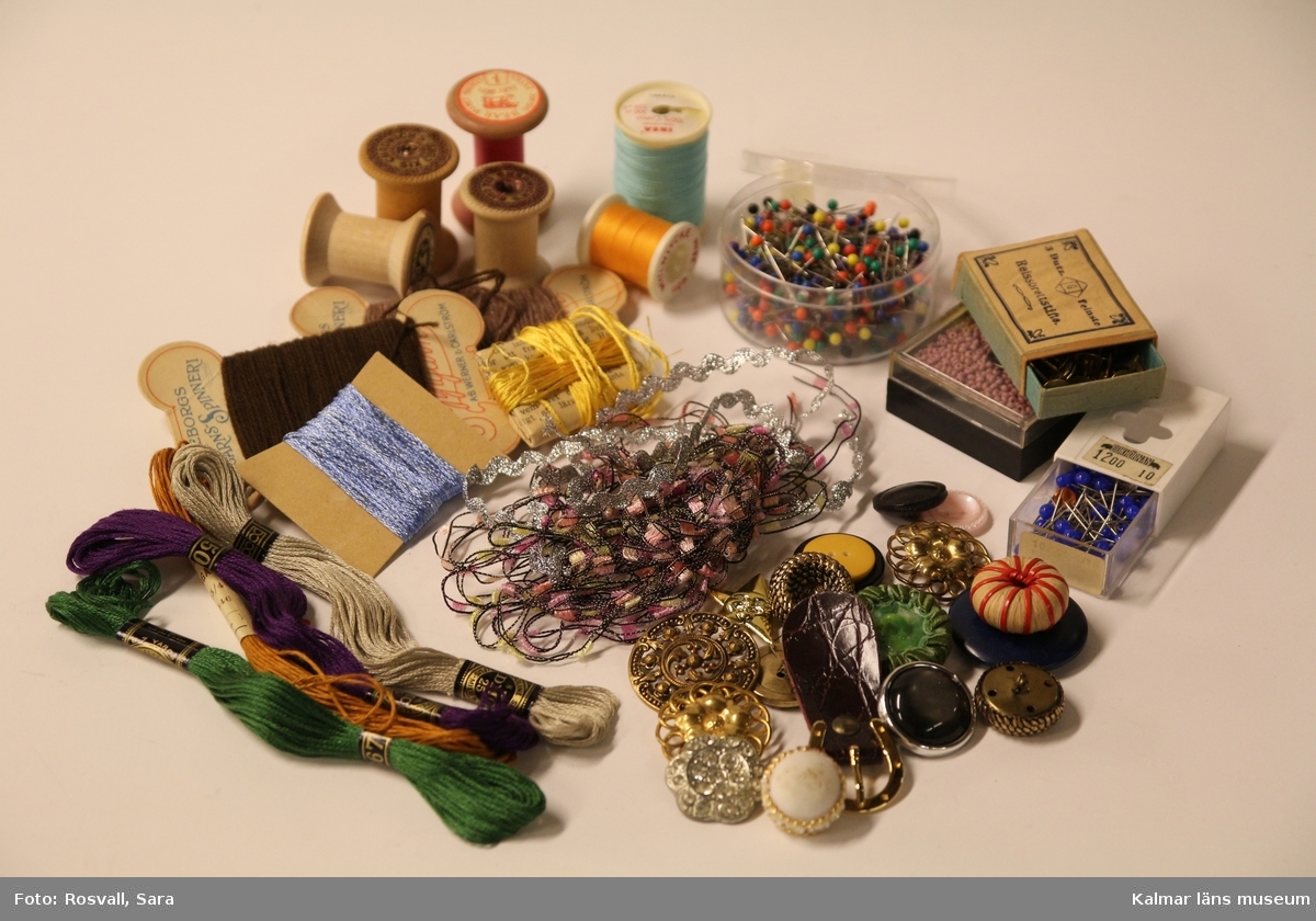 KLM 46157:502. Konstmaterial, samling. En samling knappar, trådrullar, paljetter, tygband, pärlor, häftstift m.m.