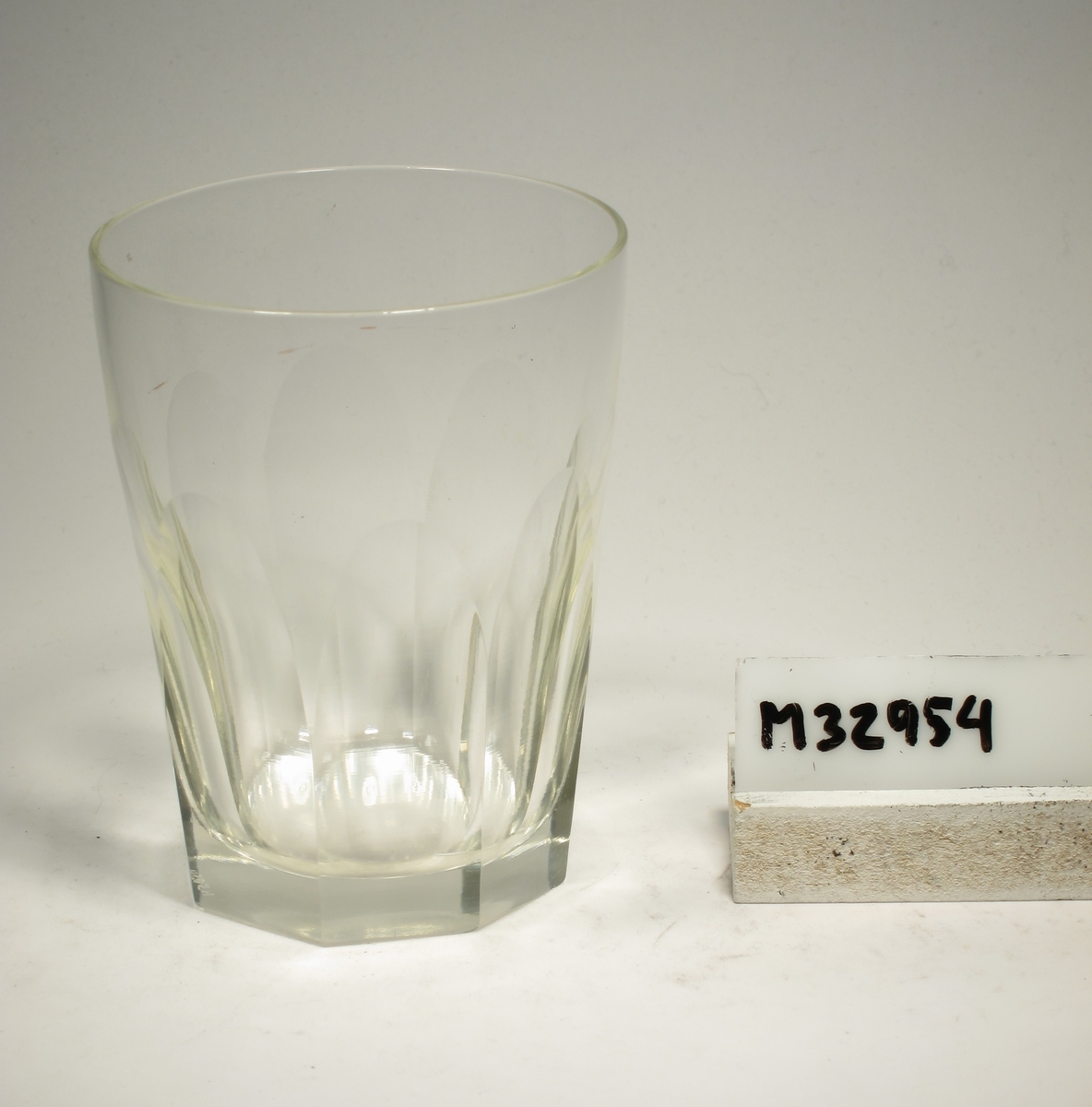 Glas med elliptisk form och slipade stående facetter runt nedre delen.