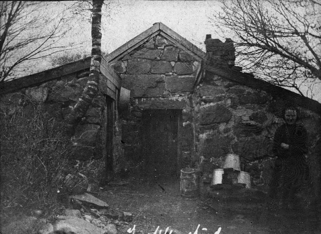 Det gamle brunnhuset på Tjensvoll. Huset står ennå i 1987. Til høgre Maja Tjensvoll.