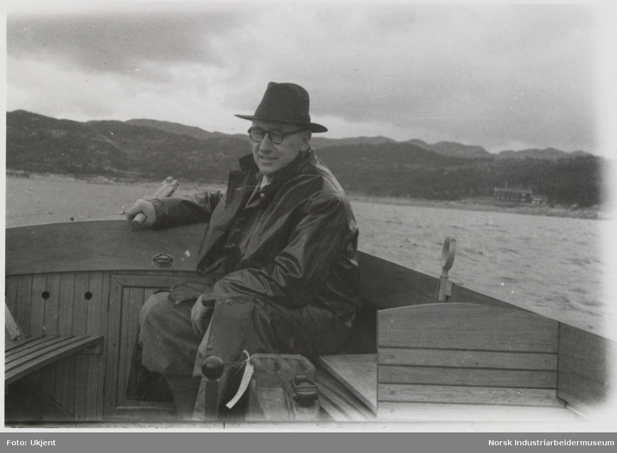 James Coward med hatt og briller styrer båt på Møsvatn