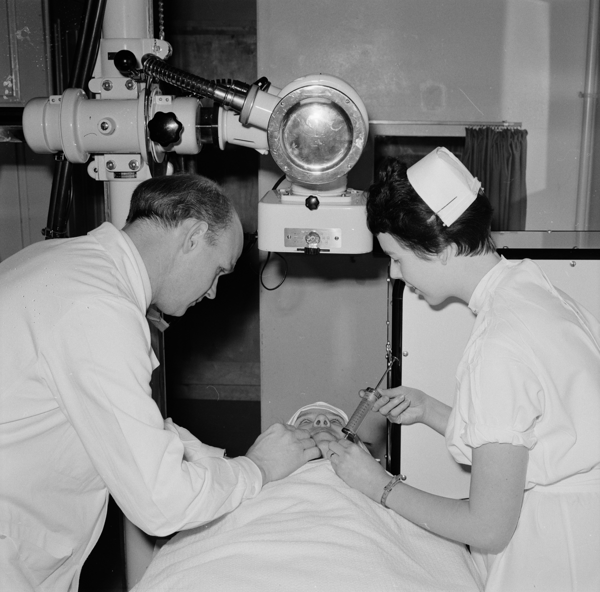 Läkaren Olof Olofsson och sjuksköterskan Karin Anens förbereder en röntgenundersökning av en hjärnpatient, Akademiska sjukhuset
