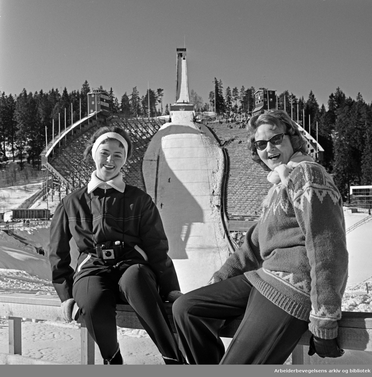 "Mor og datter, Ingrid og Ingebjørg Vestgren, koser seg i påskesola i Holmenkollen". Mars 1962.